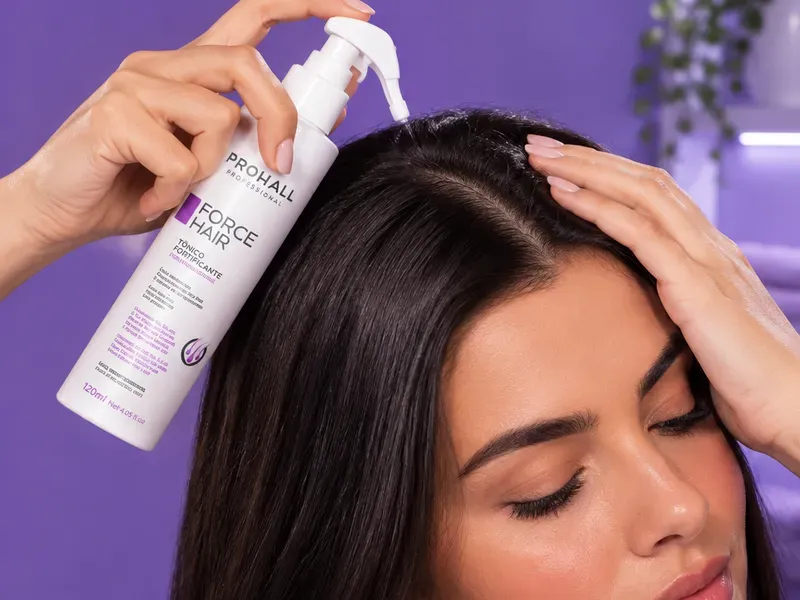 Mulher borrifando o Tônico Fortificante Force Hair direto no couro cabeludo, com o cabelo seco